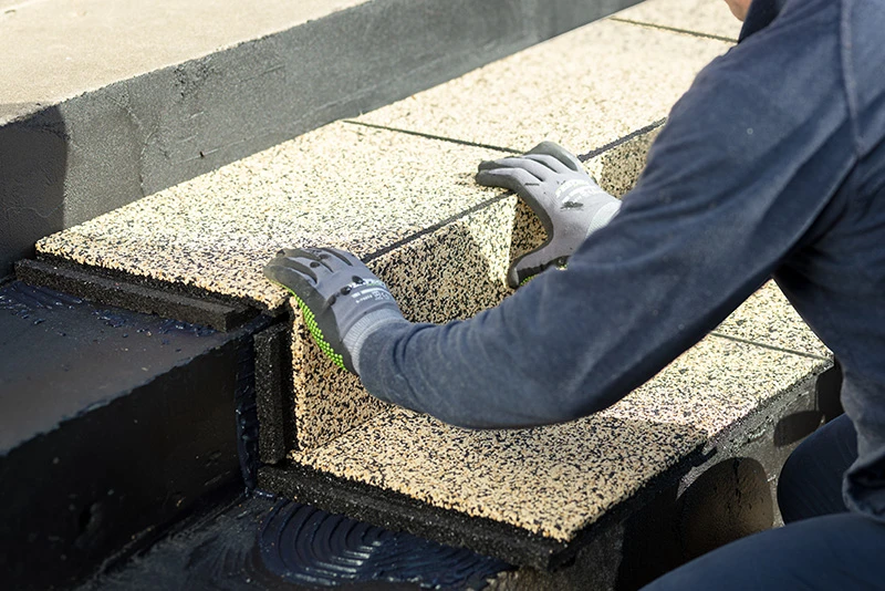 Een man legt gele Warco-pallets op de trap. De man draagt handschoenen.
