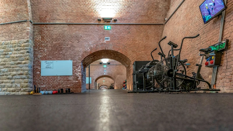 Mooie grote hal met bogen omgebouwd tot gymzaal en bedekt met bruine tegels.