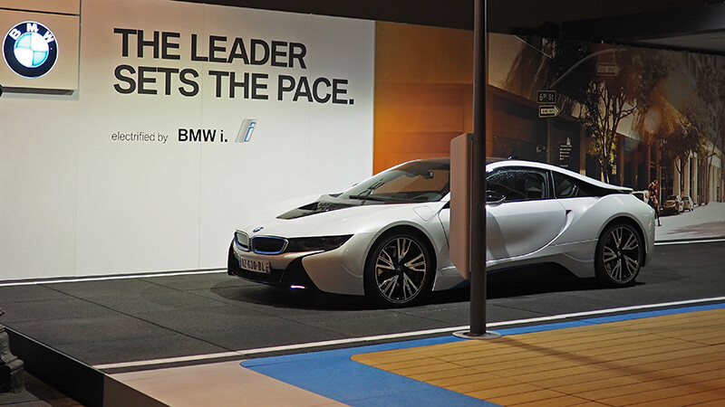 De I8 van BMW wordt gepresenteerd op een beurs. De supersportwagen staat op de zwarte beursvloer van WARCO, die is gemodelleerd naar het asfalt van een weg.
