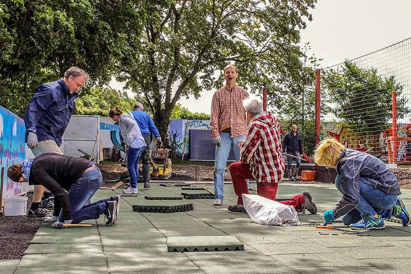 Zicht op het centrale gedeelte van een speeltuin in Olsberg, die is uitgerust met een verscheidenheid aan functies en is ontworpen om dicht bij de natuur te staan. Het centrale gedeelte bestaat uit een ruime speelplek gemaakt van groene valbeschermingsplaten met daarop een klein speelhuisje.