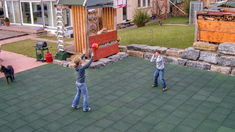Een vrouw en een tiener spelen volleybal op een groen speelveld gemaakt van balpanelen van WARCO.