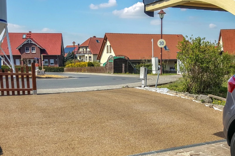 De oprit naar het pand en de parkeerplaats werden ontworpen met WARCO rubbergranulaatbestrating in het natuurlijke kleurendesign Bast & Borke. De oprit is licht hellend; de bestratingsplaten passen zich aan het terreinprofiel aan.