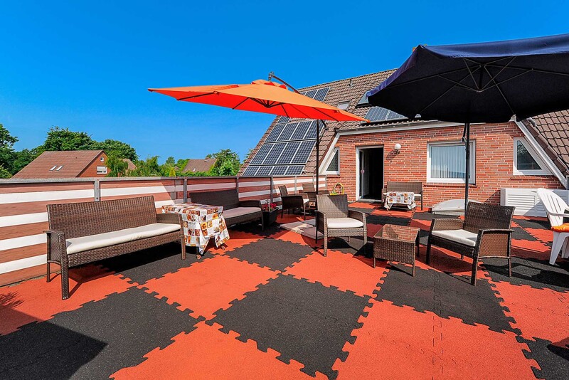 Het dakterras van Pension Nordlicht in Esens nodigt je uit om te zonnebaden en te ontspannen met verschillende zithoeken. De terrasvloer bestaat uit zwarte en rode TZ-terrastegels van WARCO. De terrasvloer is gelegd in een schaakbordpatroon.