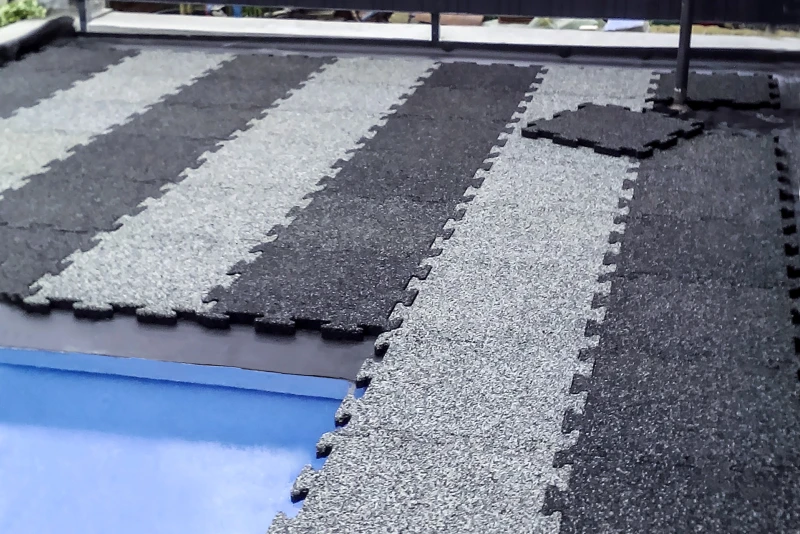 Gestreepte Warco-tegels in grijs en zwart omringen een zwembad. De installatie is nog niet voltooid.